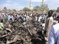 ナイジェリア北部最大の都市カノのモスク（イスラム教礼拝所）で発生した自爆攻撃や銃撃戦のあと、燃えたオートバイを見る住民（2014年11月29日撮影）。(c)AFP/AMINU ABUBAKAR