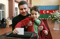 アゼルバイジャンの首都バクー（Baku）の投票所で、子どもと一緒に大統領選の投票をする男性（2008年10月15日撮影）。(c)AFP/VANO SHLAMOV
