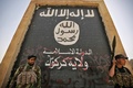 イラク・ハウィジャに進攻した際、ISの旗を描いた壁画の前に立つ、政府軍のIS掃討作戦に参加する民兵組織「人民動員隊」の隊員ら（2017年10月5日撮影）。(c)AFP/AHMAD AL-RUBAYE