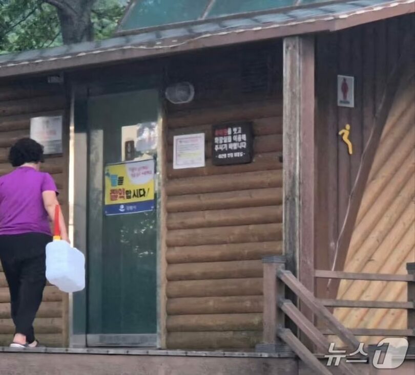 2025年7月25日、干ばつと猛暑が深刻な江原道江陵市の展望台公衆トイレで、キャンプ客が15L入りの水容器を持って水を汲む様子(c)news1