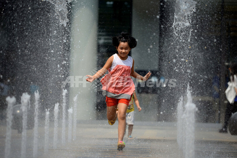 酷暑の北京、噴水で涼む子供たち