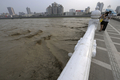 中国四川（Sichuan）省綿陽（Mianyang）で、四川大地震でできた唐家山（Tangjiashan）の「せき止め湖」の水が流れ込み水位の上がったフウ江（Fu Jiang）を見つめる男女（2008年6月10日撮影）。(c)AFP/LIU Jin