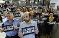 仏パリ（Paris）にあるAFP編集部で、「私はシャルリー」と書かれたプラカードを掲げ、週刊紙シャルリー・エブド（Charlie Hebdo）本社への襲撃での犠牲者に黙とうをささげるジャーナリストたち（2015年1月7日撮影）。(c)AFP/BERTRAND GUAY