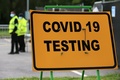 新型コロナウイルス感染症（COVID-19）の検査を示す看板と横に立つ警備員。英イングランド・ストックポートで（左奥、2020年9月16日撮影、資料写真）。(c)Lindsey Parnaby / AFP