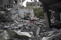 パレスチナ自治区ガザ地区（Gaza Strip）南部ラファ（Rafah）の難民キャンプ近くで、破壊された建物のがれきの中でイスラエル軍の攻撃による負傷者などを探す救助隊員（2014年8月4日撮影）。(c)AFP/MAHMUD HAMS