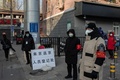 中国・北京の住宅街の入り口で、マスクを着けて入場者の身分証確認と体温検査のため待機する警備員とボランティアの人々（2020年2月3日撮影）。(c)NICOLAS ASFOURI / AFP