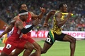 第15回世界陸上北京大会、男子4×100メートルリレー決勝。米国のタイソン・ゲイ（左奥）とマイク・ロジャーズ（左手前）がバトンパスをする中、走り抜けるジャマイカのウサイン・ボルト（2015年8月29日撮影）。(c)AFP/WANG ZHAO