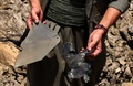 イラク北部カンディルで、クルド人武装組織「クルド労働者党（PKK）」に対するトルコ軍の空爆でできた穴から集めた金属片を見せるPKKメンバーの男性（2015年7月29日撮影）。(c)AFP/SAFIN HAMED