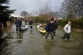 英イングランド（England）南東部バクシャー（Berkshire）州のレイズバリー（Wraysbury）で、ボートに荷物を乗せ、冠水した道路を歩いて避難する住民たち（2014年2月10日撮影）。(c)AFP/BEN STANSALL