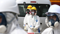 東京電力（TEPCO）は26日、福島第1原子力発電所の敷地内を報道陣に公開した。写真は第1原発4号機のそばに立つ作業員（2012年5月26日撮影）。(c)AFP/POOL/Tomohiro Ohsumi