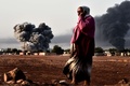 イスラム過激派組織「イスラム国（Islamic State、IS）」を標的とする米軍主導の空爆が行われたシリア北部アインアルアラブ（Ain al-Arab、クルド名：コバニ、Kobane）から立ち上る煙を、国境の反対側トルコ・シャンルウルファ（Sanliurfa）県の村ムルシトピナル（Mursitpinar）から見る女性（2014年10月13日撮影）。(c)AFP/ARIS MESSINIS