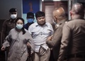タイの首都バンコクで、警察署内を母親と共に歩く民主活動家のパリット・チワラック氏（中央、2020年8月14日撮影）。(c)Lillian SUWANRUMPHA / AFP
