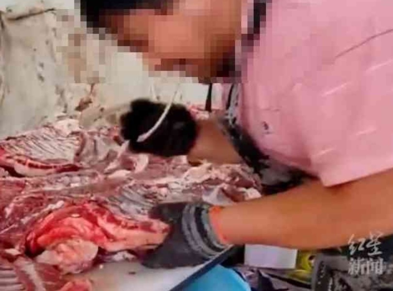 口で羊肉の骨を抜く肉屋の映像（SCMPキャプチャー）(c)news1