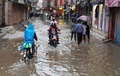 ネパールの首都カトマンズの南にあるパタンで、冠水した道路を通行する人たち（2017年8月12日撮影）。(c)AFP/PRAKASH MATHEMA
