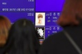 韓国ソウルの病院で、電光掲示板に映る男性アイドルグループ「SHINee（シャイニー）」のキム・ジョンヒョンさんをみつめるファンたち（2017年12月19日撮影）。(c)AFP PHOTO / JUNG Yeon-Je
