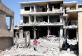 シリア南部ダルアー県北部の反体制派の拠点ナワで、政権軍の空爆で破壊されたビルの前を歩く少年（2018年7月11日撮影）。(c)AFP PHOTO / Ahmad al-Msalam