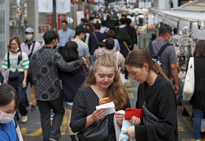 屋外マスク着用義務が解除されて初めての週末となった先月2日、ソウル・明洞通りで外国人観光客がマスクを外して料理を味わっている(c)NEWSIS