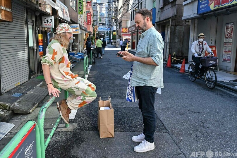 東京・秋葉原で、中古ゲームショップ巡りの最中に休憩するリュドビク・シャルルさん（右）とブノア・テブニさん（2023年10月10日撮影）。(c)Richard A. Brooks / AFP