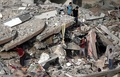 パレスチナ自治区ガザ地区（Gaza Strip）ガザ市（Gaza City）で、ミサイル着弾で倒壊した集合住宅のがれきの中から私物を拾い集める人々（2014年8月24日撮影）。(c)AFP/THOMAS COEX