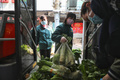 中国中部・湖北省武漢で、住民に届ける野菜を配送車に積み込むスーパーマーケットの従業員たち（2020年3月5日撮影）。(c)AFP