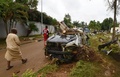 コートジボワールのアビジャンで、車の残骸のそばを歩く人々（2018年6月19日撮影）。(c)AFP PHOTO / Sia KAMBOU