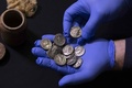 ユダヤ砂漠にあるムラバアト洞窟の発掘現場で見つかった15枚の銀貨。出土した筒（左上）の中に入っていた（2022年12月13日撮影）。(c)MENAHEM KAHANA / AFP