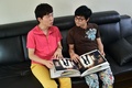 韓国ソウルの自宅で、自分たちの結婚式の写真アルバムを眺める金趙光秀さん（右）と金承煥さんのカップル（2015年7月15日撮影）。(c)AFP/JUNG YEON-JE
