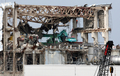 東京電力（TEPCO）は26日、福島第1原子力発電所の敷地内を報道陣に公開した。写真は第1原発4号機の前を歩く細野豪志（Goshi Hosono）原発事故担当相（赤いヘルメット）と報道陣ら（2012年5月26日撮影）。(c)AFP/POOL/Tomohiro Ohsumi