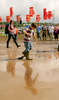 2007年6月22日、サマセット（Somerset）のピルトン（Pilton）で開催されている「グラストンベリー・フェスティバル（Glastonbury Festival）」で泥の上を歩く来場者。(c)AFP/CARL DE SOUZA
