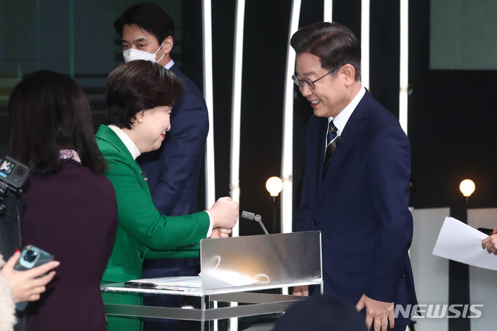 討論を前に握手を交わすシム・サンジョン（沈相奵）氏（左）とイ・ジェミョン（李在明）氏(c)NEWSIS