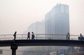中国遼寧省瀋陽で、スモッグでかすむ建物と、歩道橋をわたる住民たち（2015年11月8日撮影）。(c)AFP