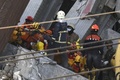 地震で倒壊した台湾南部・台南市の集合住宅で、がれきの中から救出された28歳のベトナム人女性を運び出す救助隊員たち（2016年2月8日撮影）。(c)AFP/SAM YEH