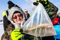 米ミネソタ州ブレーナードにあるガル湖で行われた氷上釣り大会で、釣った魚を見せる参加者（2022年1月29日撮影）。(c)Kerem Yucel / AFP