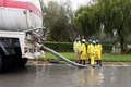 アラブ首長国連邦（UAE）アブダビで、豪雨で冠水した道路の排水に当たる作業員ら（2016年3月9日撮影）。(c)AFP
