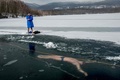 チェコ・テプリツェ近郊のバルボラ湖で、凍結した湖面の下に潜って泳ぐフリーダイバーのデービッド・ベンツルさんを見守る友人。ベンツルさんは、氷の下で長距離を泳ぐギネス世界記録を目指して練習している（2021年2月13日撮影）。(c)Michal Cizek / AFP