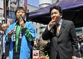 都内即売会で福島県いわき市産のイチゴを食べる枝野幸男（Yukio Edano）官房長官（右）と、トマトを食べるお笑いコンビ南海キャンディーズのしずちゃんこと山崎静代（Shizuyo Yamasaki）さん（左、2011年4月12日撮影）。(c)AFP/Yoshikazu TSUNO
