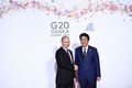 大阪で開催中の20か国・地域（G20）首脳会議の歓迎行事で、ロシアのウラジーミル・プーチン大統領（左）を迎える安倍晋三首相（右、2019年6月28日撮影）。(c)Brendan Smialowski / AFP