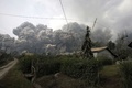 インドネシアの北スマトラ（North Sumatra）州カロ（Karo）で、シナブン山（Mount Sinabung）の噴火に伴う巨大な高温の火山灰雲に飲み込まれる村（2014年2月1日撮影）。(c)AFP/CHAIDEER MAHYUDDIN