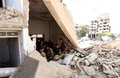 シリア政府軍が包囲してきたシリア・ダラヤで、損壊した建物の入り口に集まった政府軍の兵士ら（2016年8月26日撮影）。(c)AFP/Youssef KARWASHAN