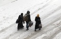 シリア北西部イドリブ県マーレトヌーマンで、雪に覆われた道を歩く人々（2016年12月21日撮影）。(c)AFP/Mohamed al-Bakour