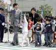 「春の全国交通安全運動中央大会」で小学生と手をつないで横断歩道を歩く麻生太郎（Taro Aso）首相（2009年4月13日撮影）。(c)AFP/Yoshikazu TSUNO