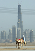2007年４月2日、ドバイ（Dubai）で建設中の超高層ビル｢ブルジュ・ドバイ（Burj Dubai）｣の前を通るラクダのキャラバン。(c)AFP/KARIM SAHIB