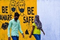 インド・ムンバイで、新型コロナウイルス感染拡大へ注意を呼び掛ける壁画の前をマスクを着けて歩く人（2020年3月23日撮影）。(c)Indranil MUKHERJEE / AFP