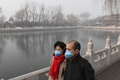 スモッグに覆われた中国・北京の湖畔を歩く夫婦（2017年1月1日撮影）。(c)AFP/GREG BAKER