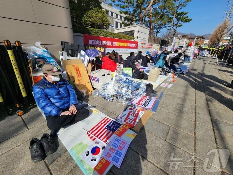 13日午前9時30分ごろ、憲法裁判所前歩道でレジャーシートを敷いて座り込みを続けるデモ隊(c)news1