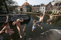 オランダ・スキーダム（Schiedam）のスヒー（Schie）川に飛び込む地元の子どもたち（2013年7月22日撮影）。(c)AFP/ANP/JERRY LAMPEN