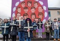 英領北アイルランド・ロンドンデリーで、1972年にカトリック系住民が英治安部隊に射殺された「血の日曜日事件」の犠牲者を描いた壁画の前で十字架を持つ人々（2022年1月30日撮影）。(c)Paul FAITH / AFP