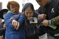 台湾の台南で、地震で倒壊した集合住宅から男子学生の遺体が収容された後、息子の写真を手に遺体に近づこうとする母親（2016年2月10日撮影）。(c)AFP