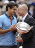 全仏オープンテニス2009（%%French Open 2009%%）男子シングルス決勝。大会第2シードのロジャー・フェデラー（%%Roger Federer%%、スイス）は、大会第23シードのロビン・ソデルリング（%%Robin Soderling%%、スウェーデン）と対戦。フェデラーは6-1、7-6、6-4で全仏初優勝を果たし、ピート・サンプラス（%%Pete Sampras%%、米国）氏の持つグランドスラム最多優勝記録（14勝）に並ぶと同時に、史上6人目の生涯グランドスラム（4大大会全制覇）を達成した。写真は表彰式で元テニス選手のアンドレ・アガシ（%%Andre Agassi%%）氏からトロフィーを授与されるロジャー・フェデラー（左）。（2009年6月7日撮影）(c)AFP/BERTRAND GUAY