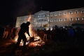 ギリシャの首都アテネの国会議事堂の前で、年金改革などに抗議し火の中に枝を投げる農業従事者（2016年2月12日撮影）。(c)AFP/LOUISA GOULIAMAKI